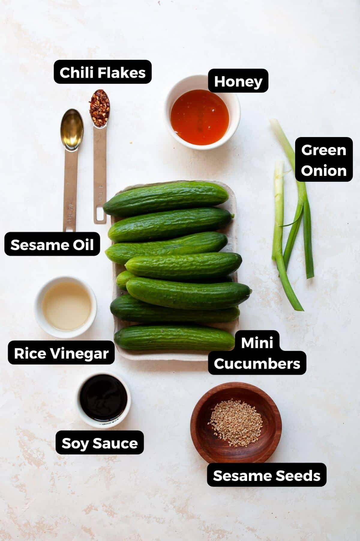 all ingredients in salad including cucumbers, green onions, rice vinegar, soy sauce, sesame seeds, sesame oil, red chili flakes, and honey