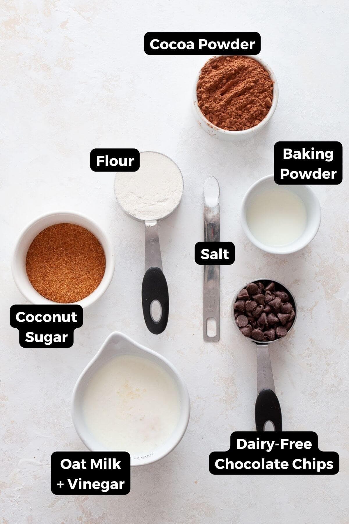 Ingredients for vegan lava cakes: flour, cocoa powder, coconut sugar, baking powder, salt, oat milk with vinegar, and dairy-free chocolate chips.