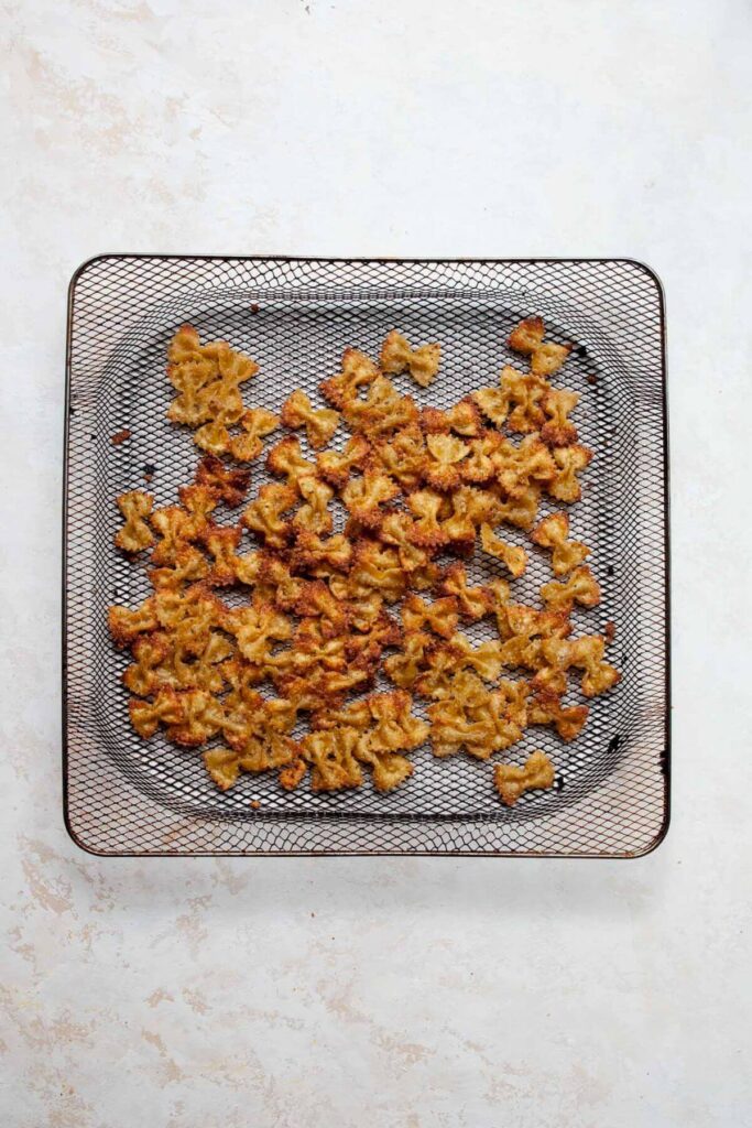 crispy pasta chips in air fryer basket after air frying