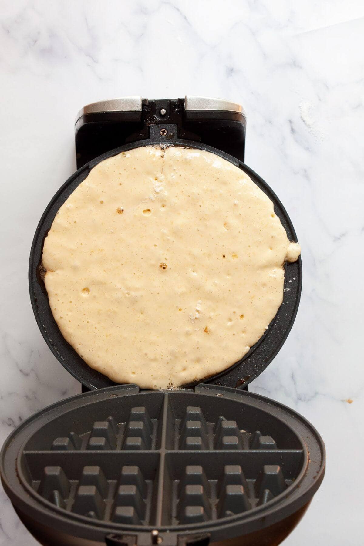 Dairy-free waffle batter poured into a hot waffle iron.