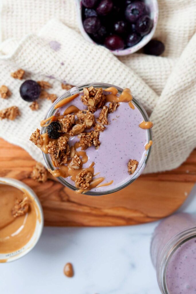 healthy blueberry smoothie with granola and peanut butter on top