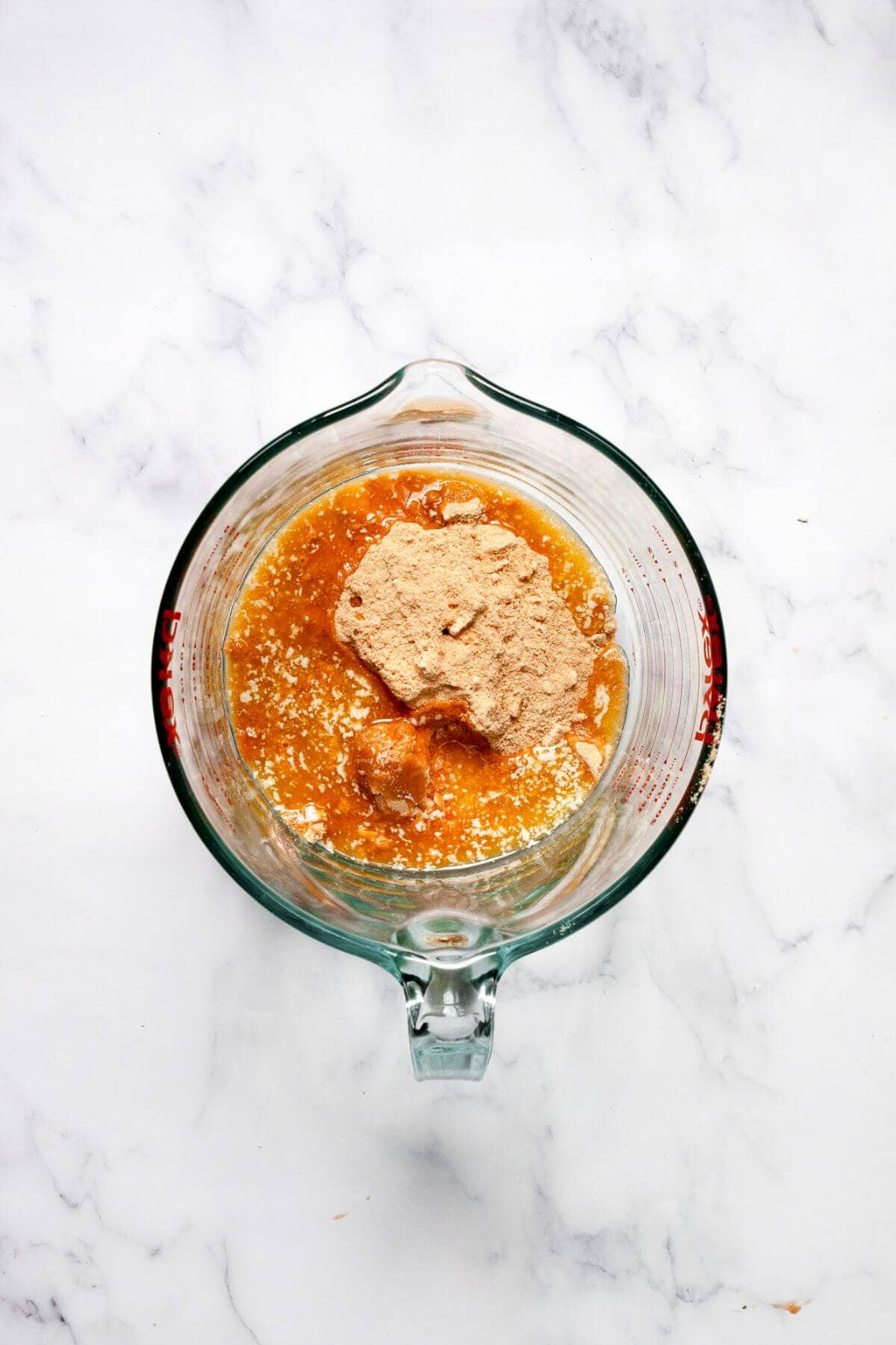 Graham cracker crumbs mixed with melted butter and brown sugar in a glass bowl.