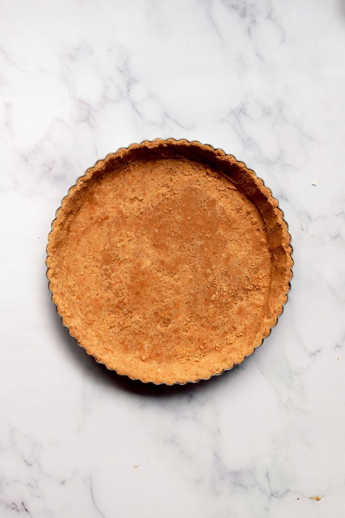 Par-baked graham cracker crust cooling in a tart pan.