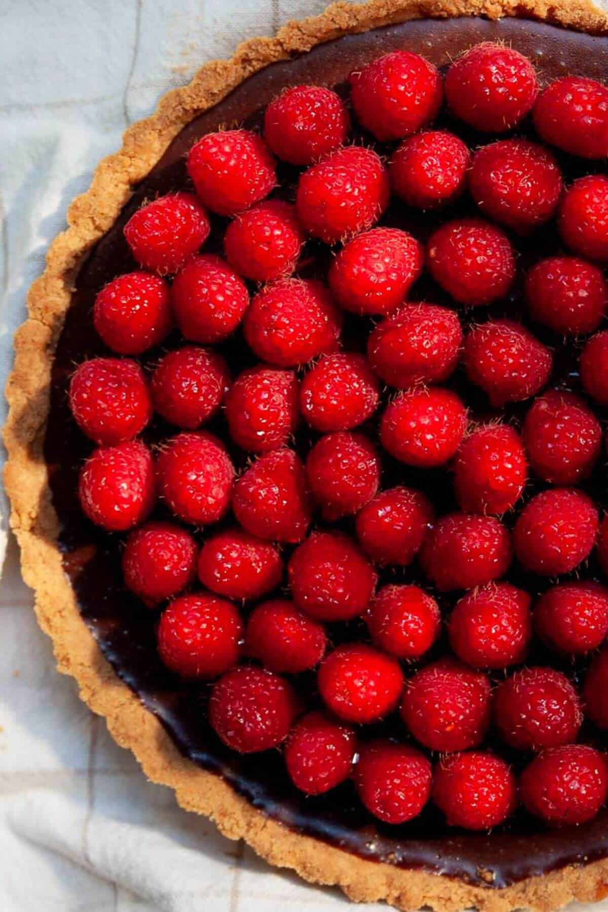 Easy dark chocolate raspberry tart with fresh raspberries glazed in honey.