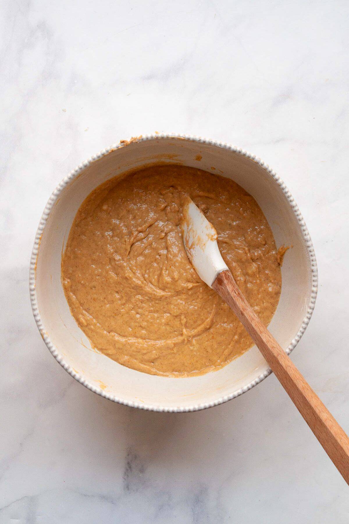Dairy-free banana bread batter in a mixing bowl, made with coconut oil and mashed bananas.
