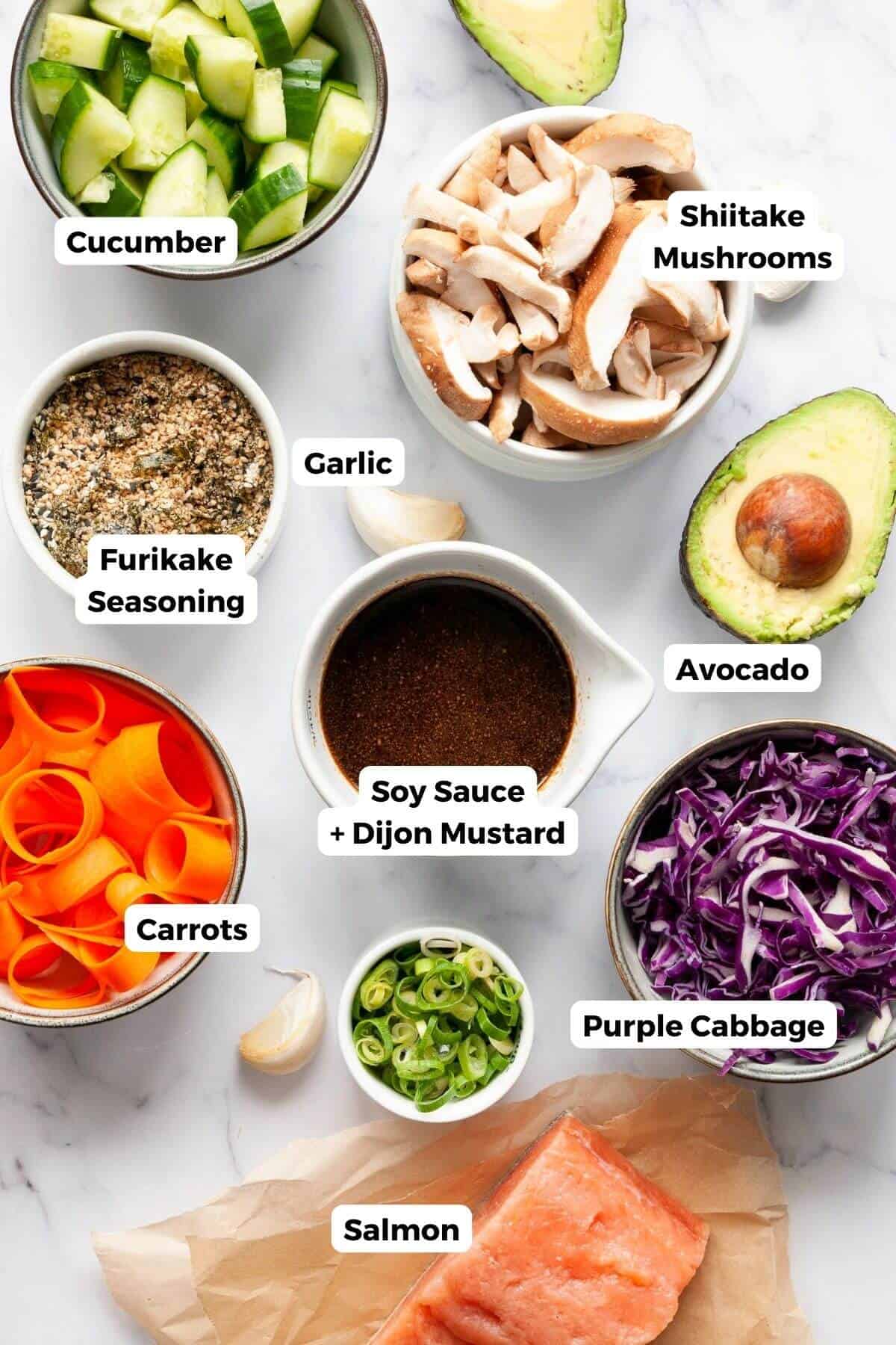 all ingredients furikake salmon bowls including salmon, mushrooms, furikake seasoning, avocado, carrots, purple cabbage, garlic, ginger, honey soy dressing, and cucumber