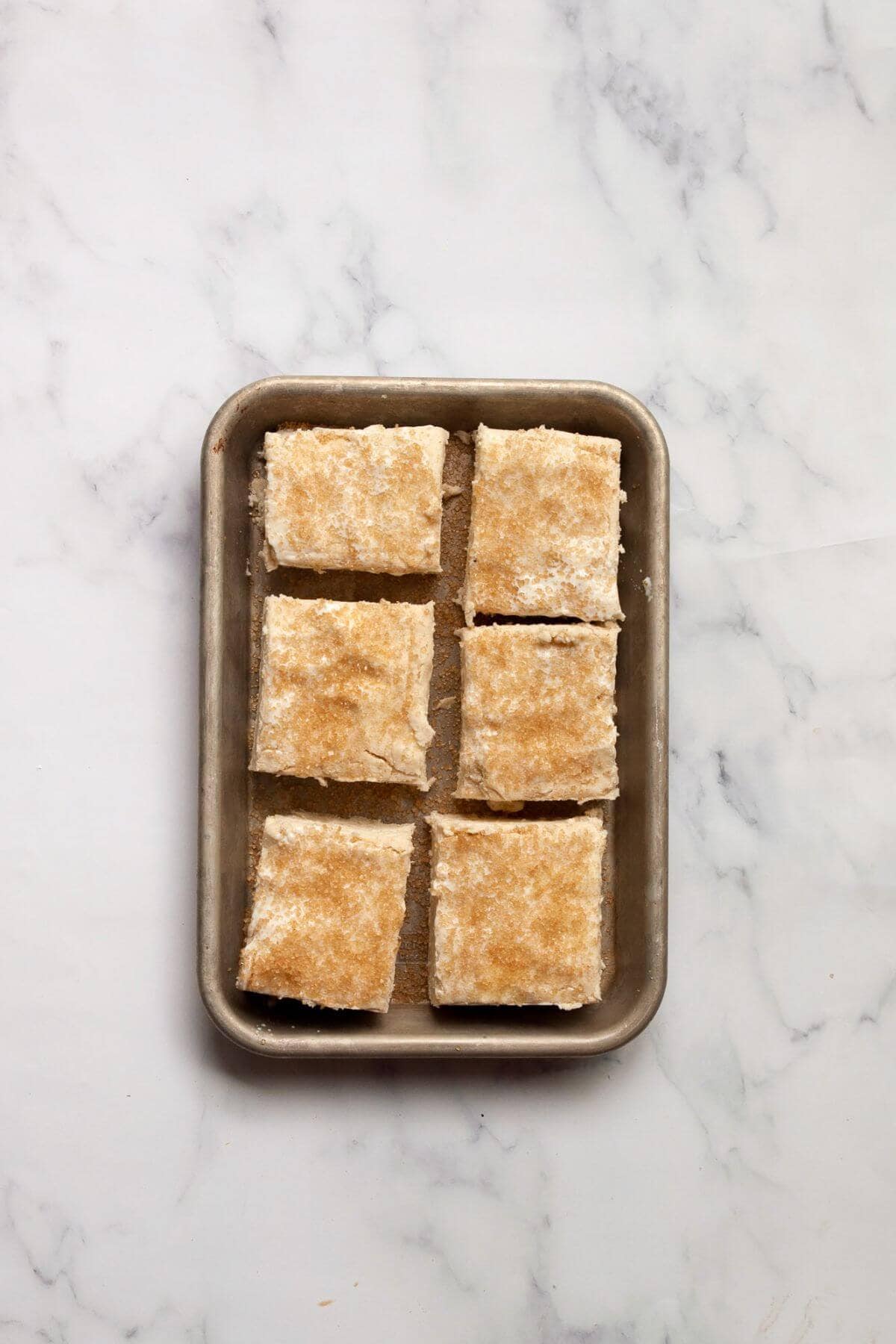 Gluten-free buttermilk biscuits topped with course sugar unbaked on a baking tray.
