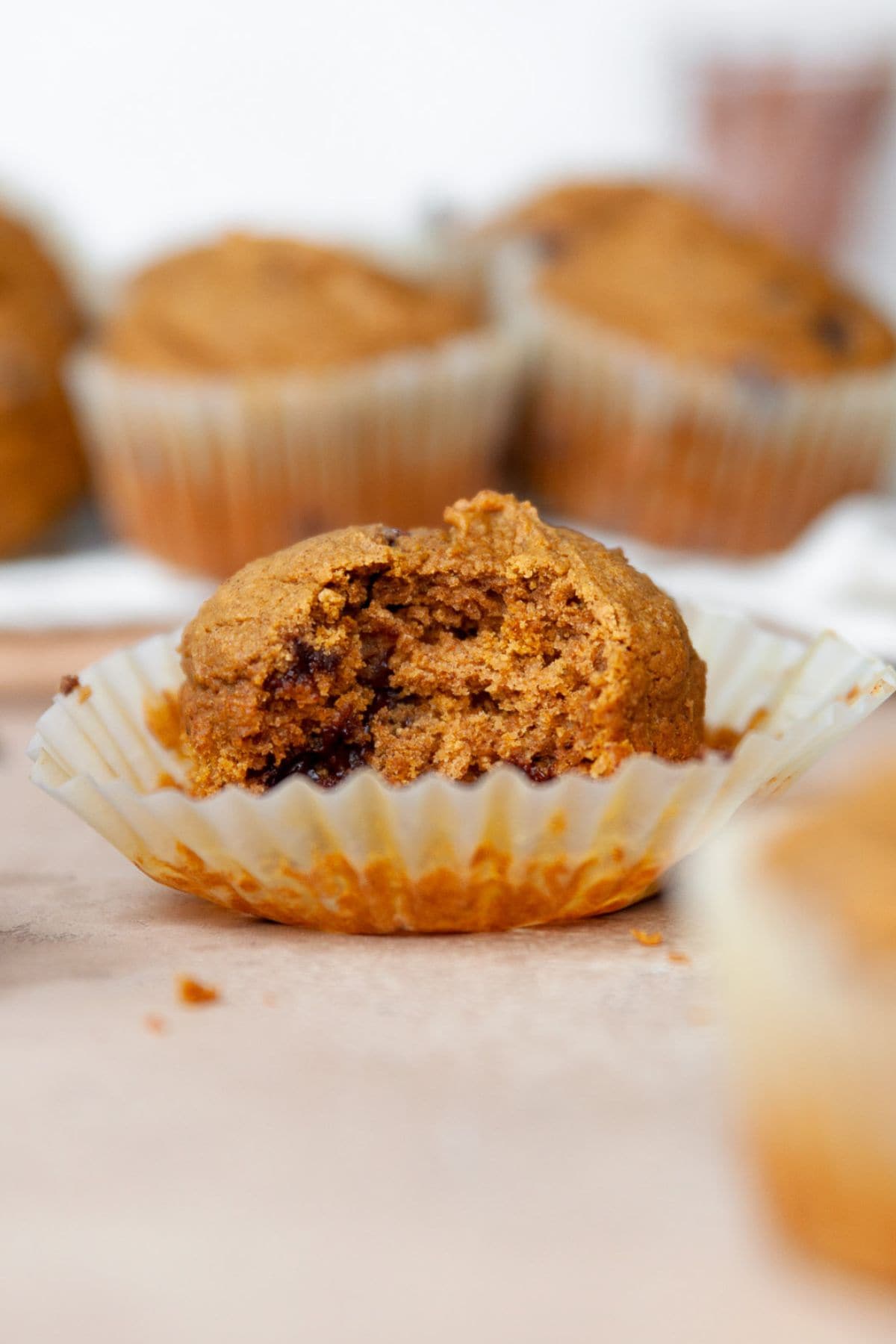 Healthy oat flour pumpkin muffin with a bite taken out, showing a soft crumb.