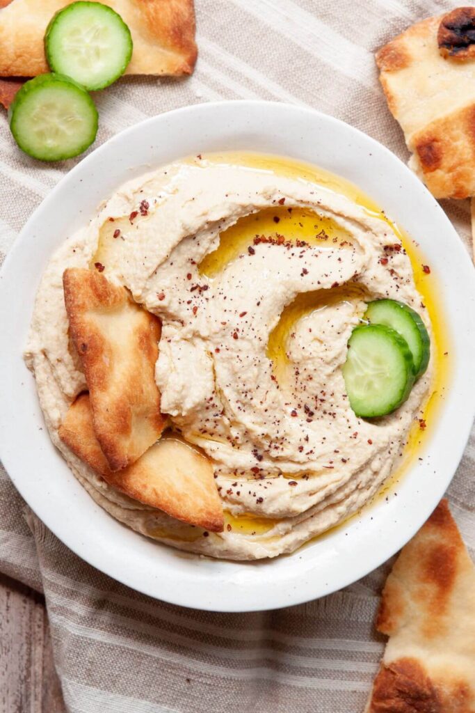 homemade blender hummus in a bowl with pita chips and crudité