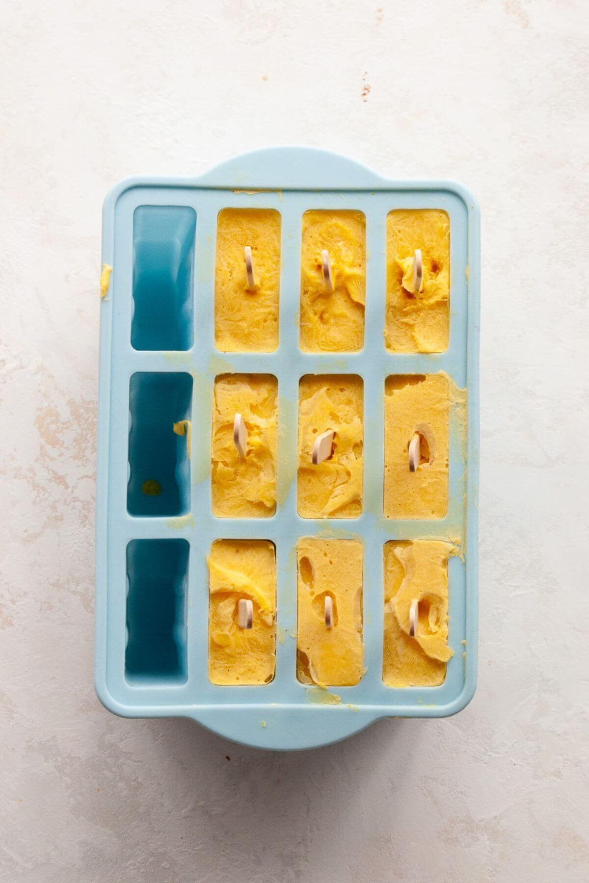 Frozen mango popsicles set in a popsicle mold, ready to be enjoyed.