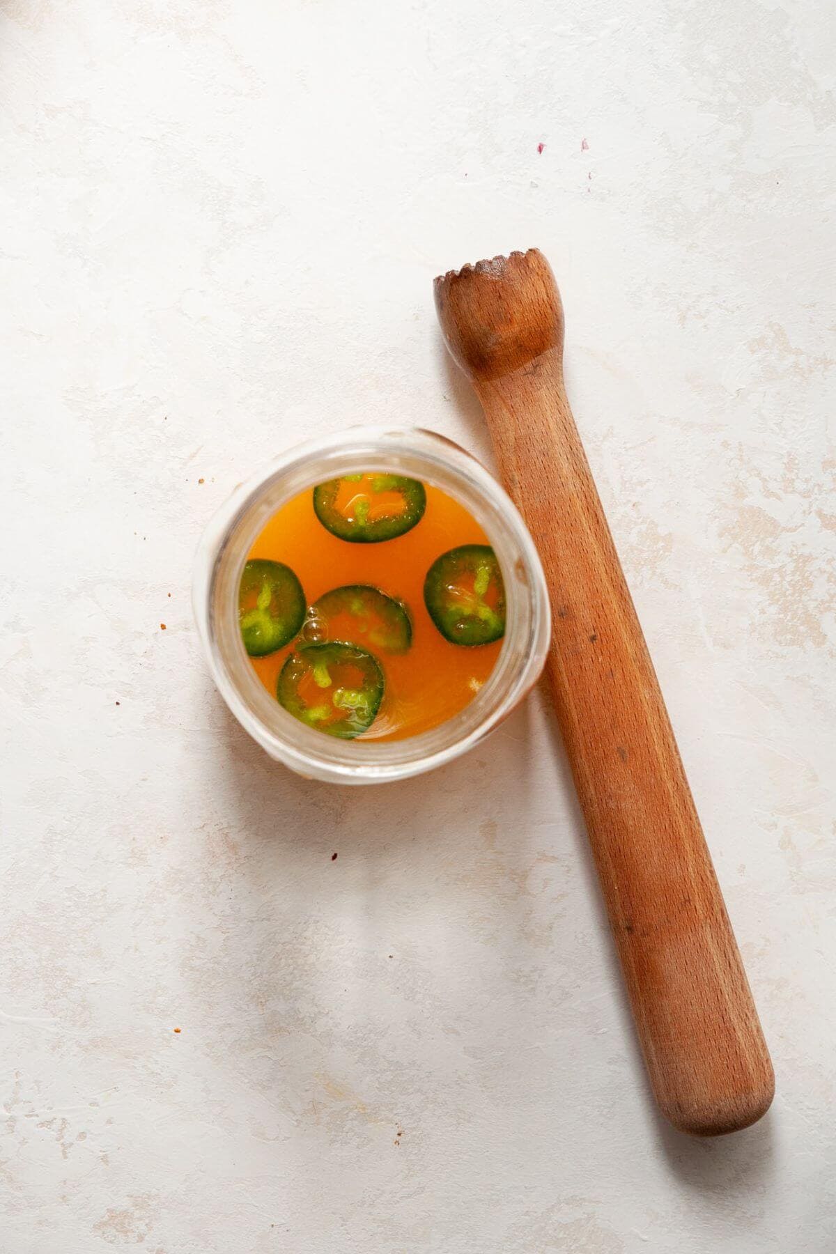 Muddling jalapeños to make spicy mango juice and tequila.