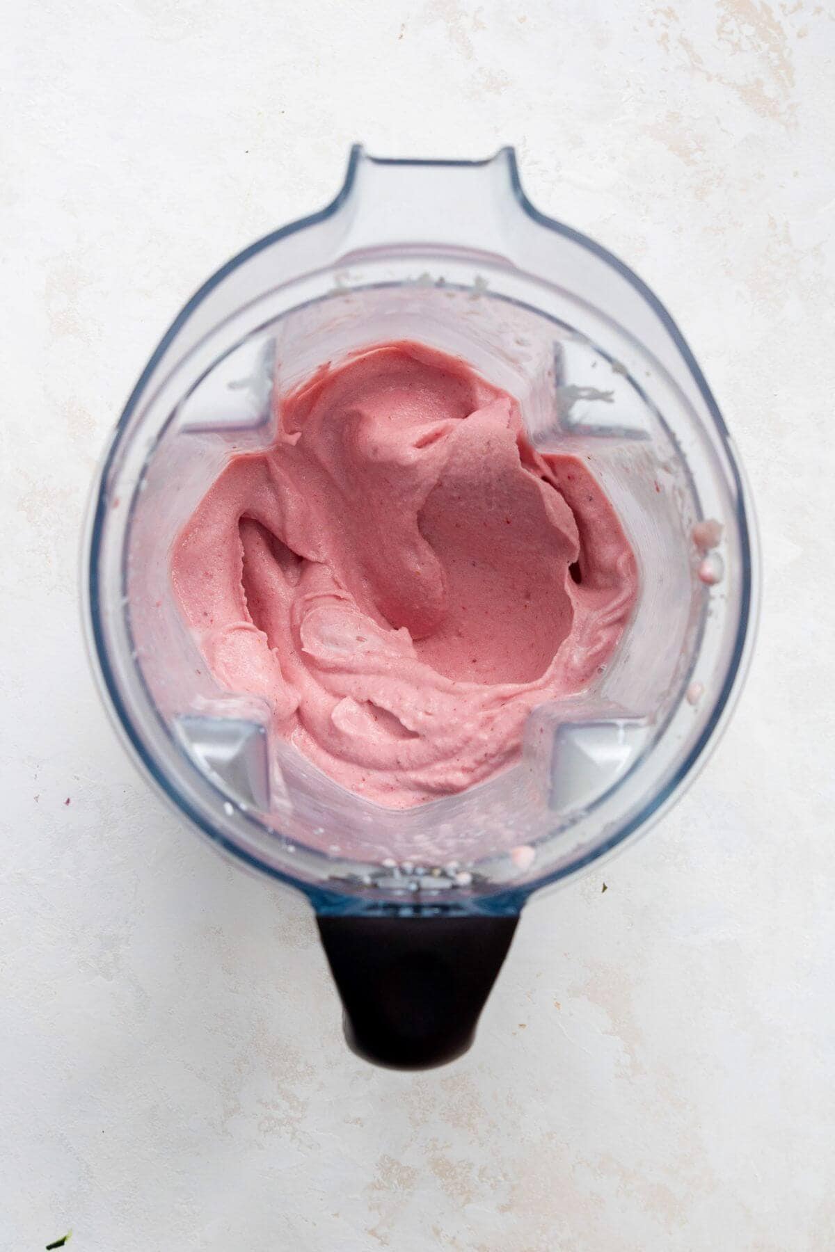 Blended pink smoothie thick enough to hold its shape in the blender jar.
