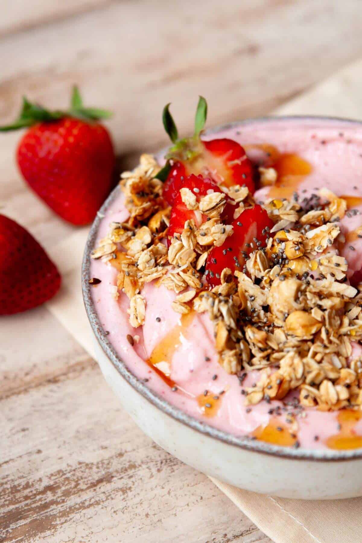 Strawberry smoothie bowl topped with granola and fresh strawberries.