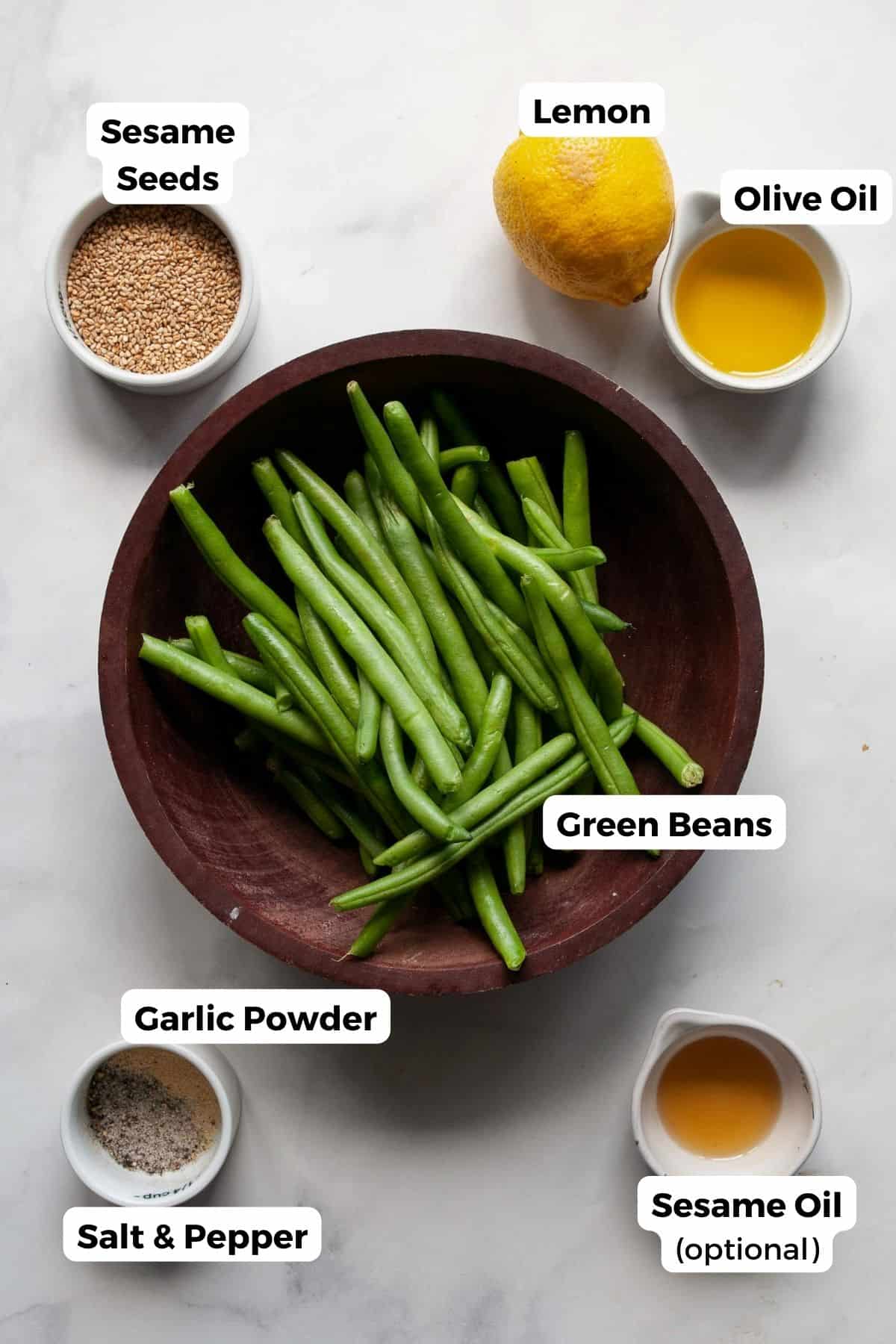 Ingredients for air fryer green beans: fresh green beans, olive oil, garlic powder, salt, pepper, lemon, sesame oil, and sesame seeds.