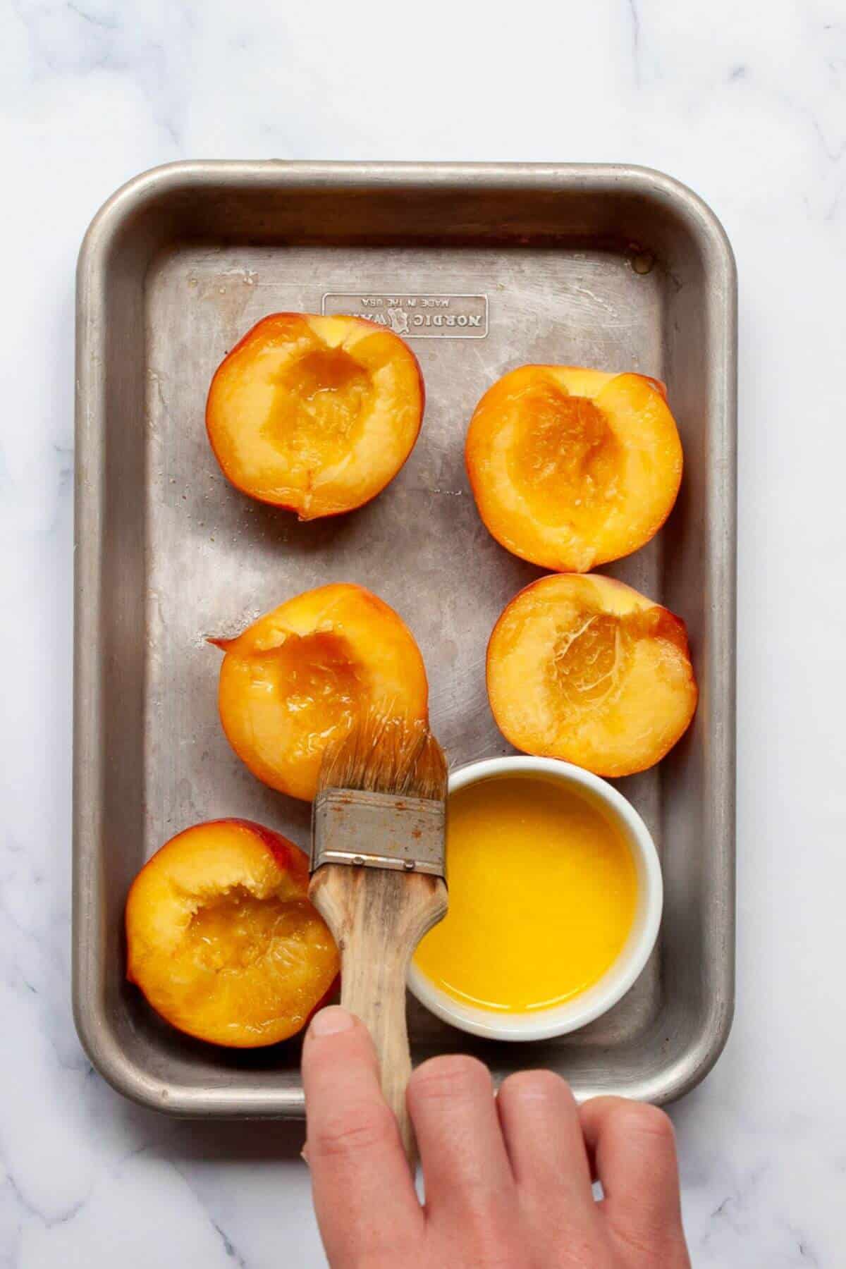 Brushing melted butter on to the tops of pitted peach halves.