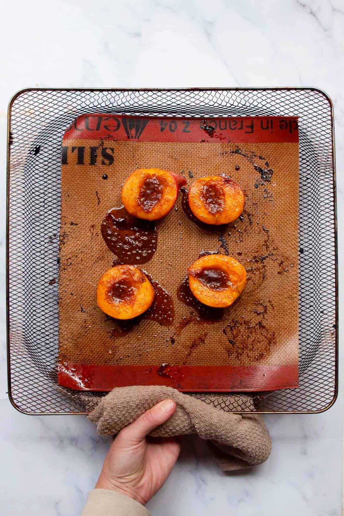 Caramelized peaches in air fryer basket after baking.
