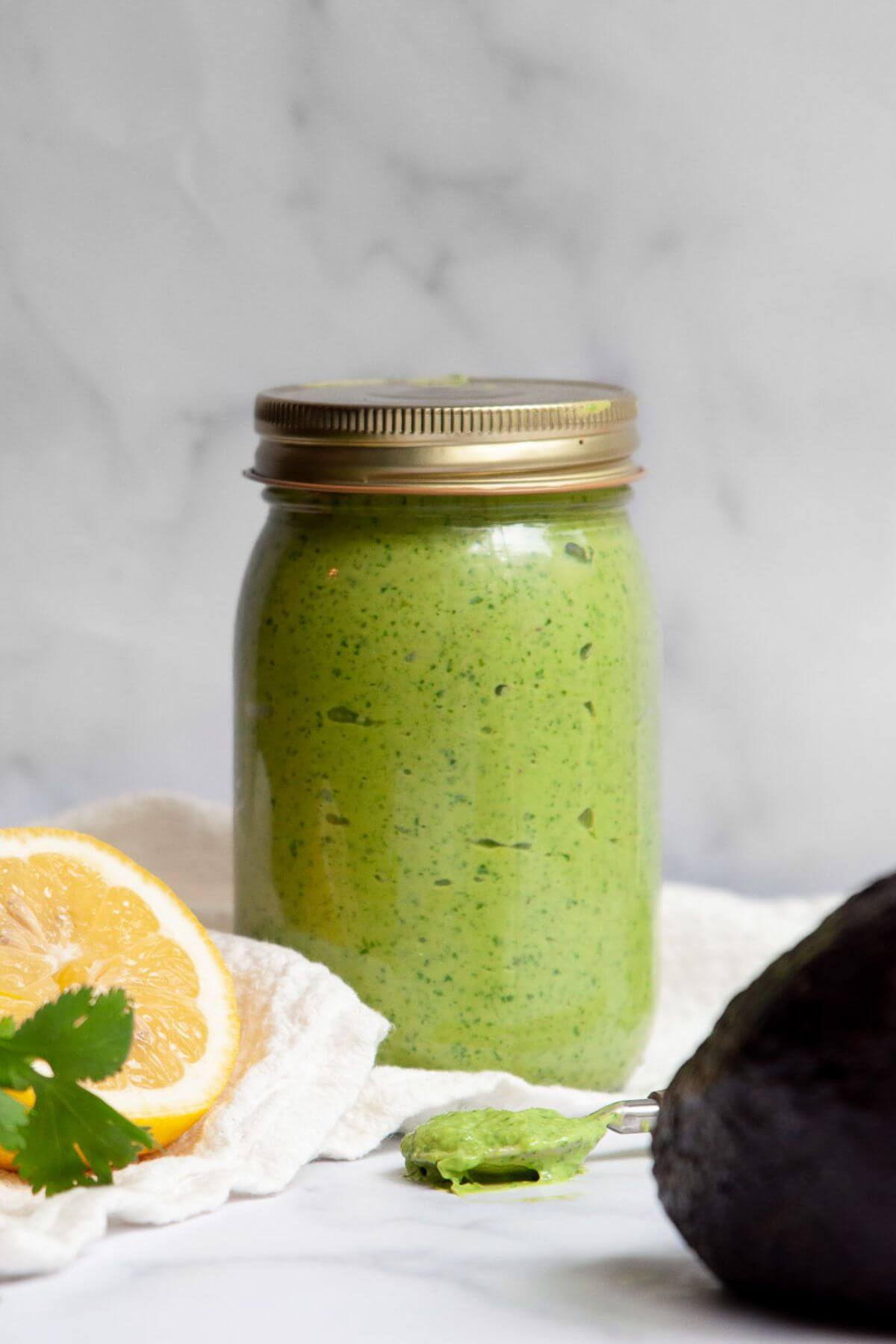 Glass jar of homemade avocado dressing without mayo or anchovies.