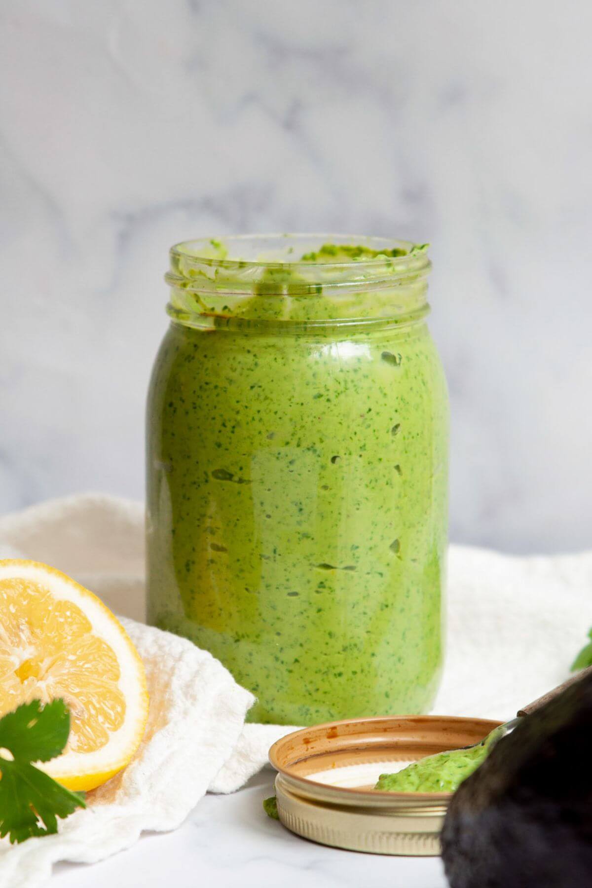 Mason jar of avocado green goddess dressing made with Greek yogurt and fresh herbs.