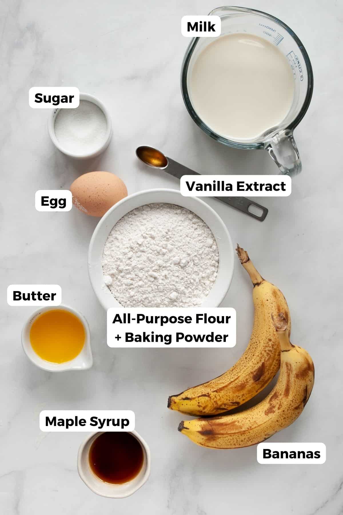 Banana foster pancake ingredients including milk, flour, butter, maple syrup, vanilla, egg, sugar, and ripe bananas.