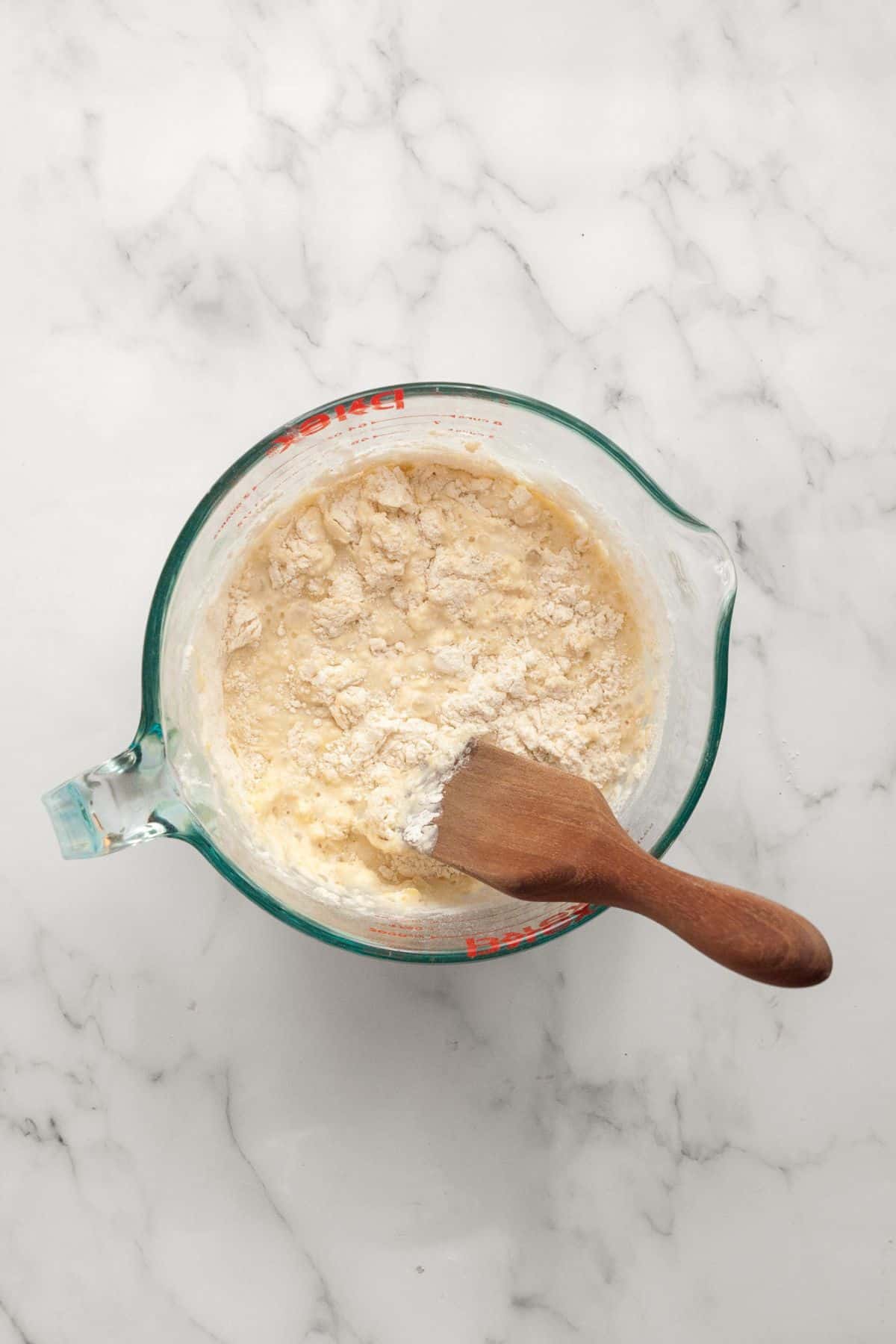 Adding dry ingredients to the wet ones in a mixing bowl.