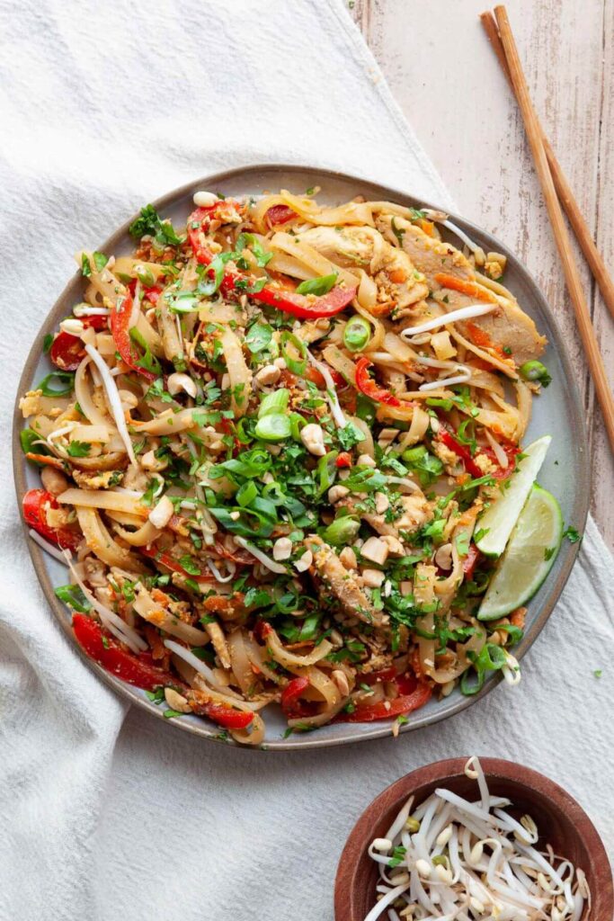 healthy chicken pad Thai on a plate with green onion and crushed peanuts