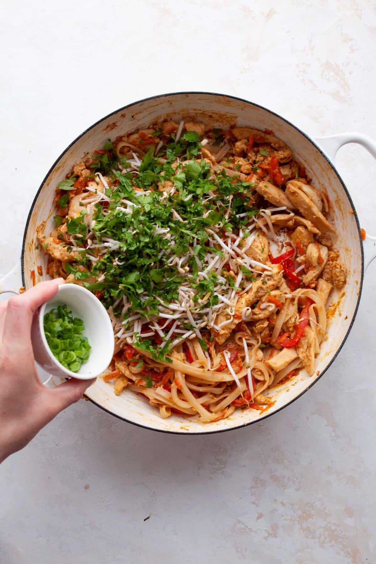Adding fresh cilantro, bean sprouts, and green onion to the pan.