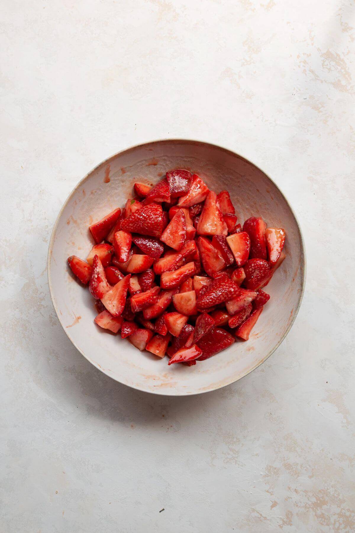 Fresh or frozen strawberries tossed with lemon juice, cornstarch, and coconut sugar in a white mixing bowl.
