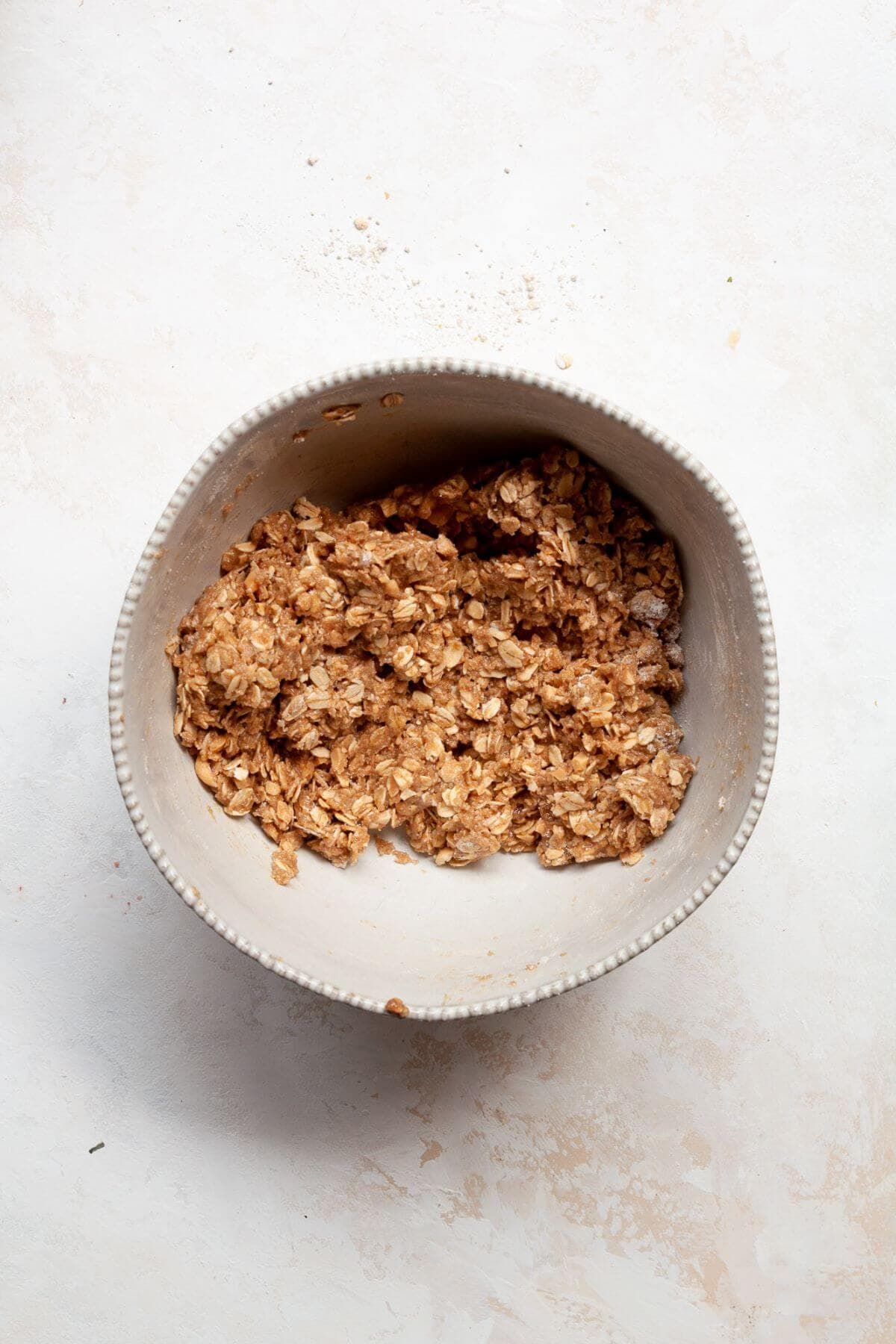 Oat flour crumble topping mixed together in a bowl with rolled oats, coconut sugar, and walnuts.