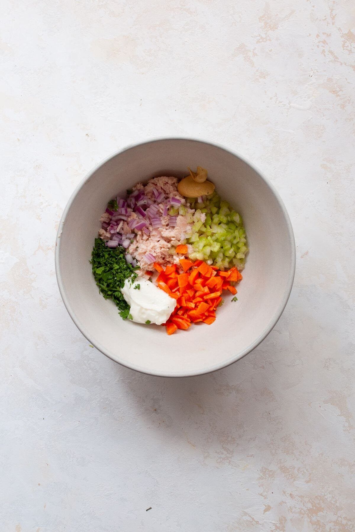 Healthy no mayo tuna salad ingredients in a mixing bowl before tossing.