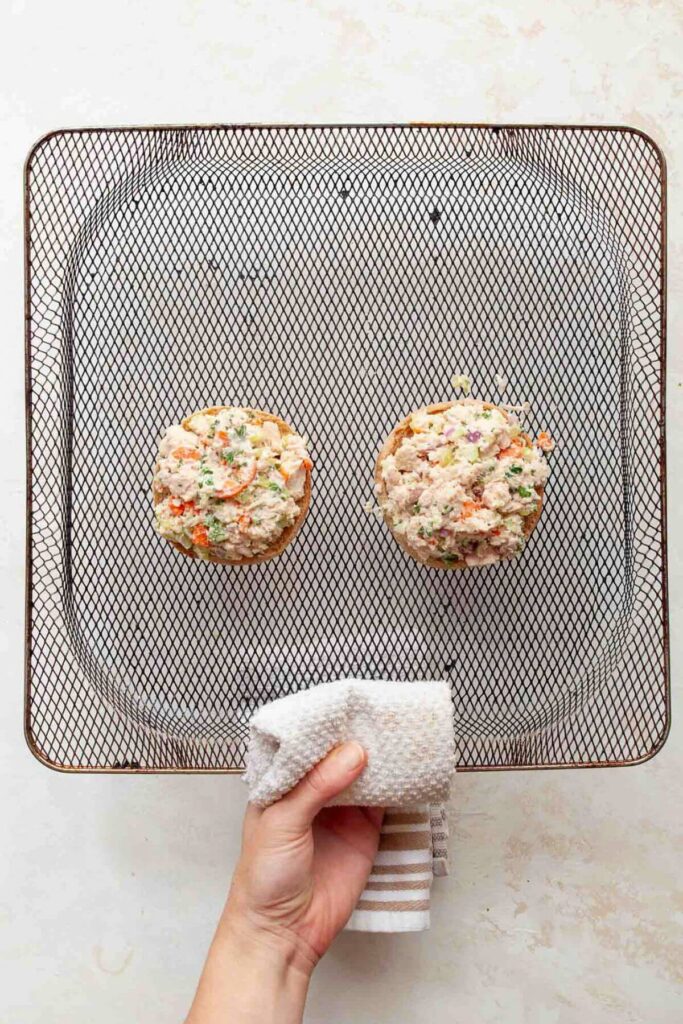 tuna salad on top of toasted english muffin halves in air fryer basket