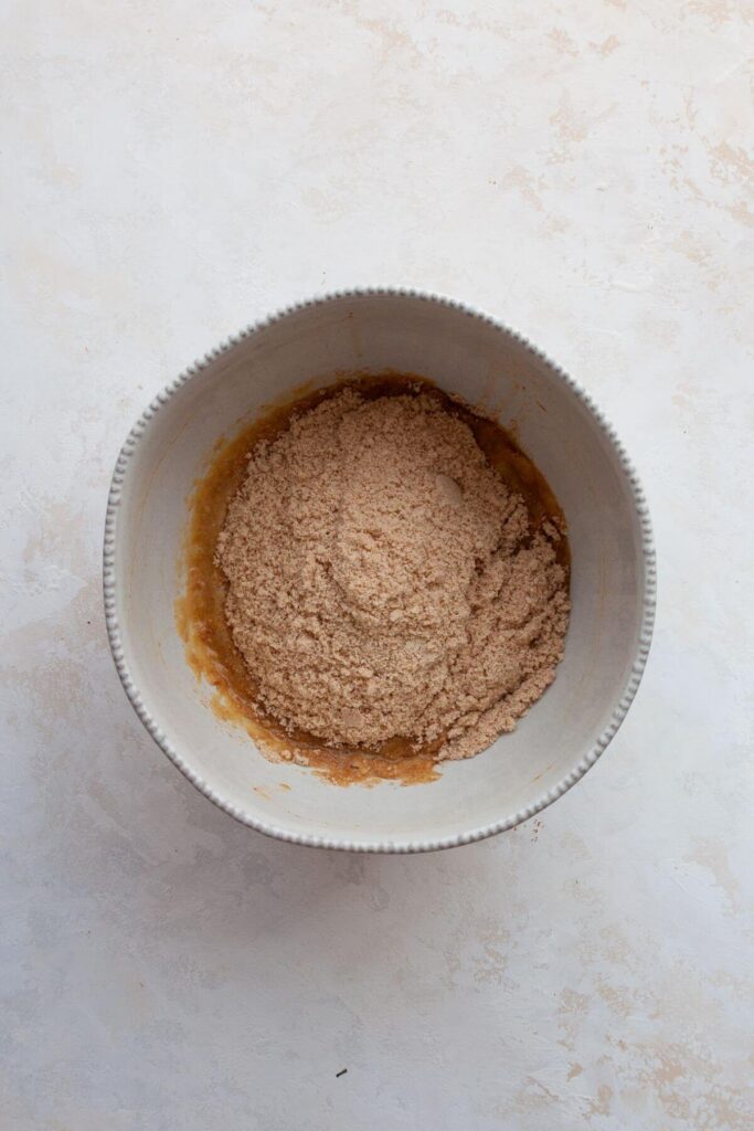 adding almond flour to the wet ingredients in a mixing bowl