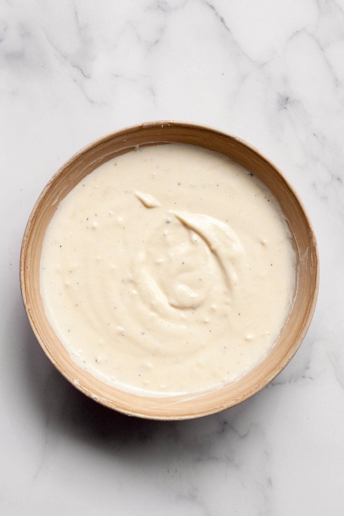 Greek yogurt Caesar dressing being whisked together in a small white bowl