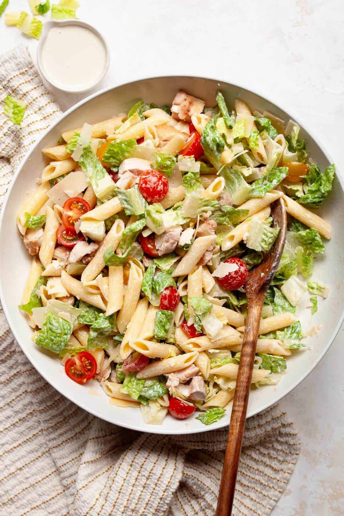 high-protein, healthy chicken Caesar pasta salad with rotini, grilled chicken, cherry tomatoes, romaine lettuce, and shaved parmesan tossed in a creamy homemade dressing made without mayo