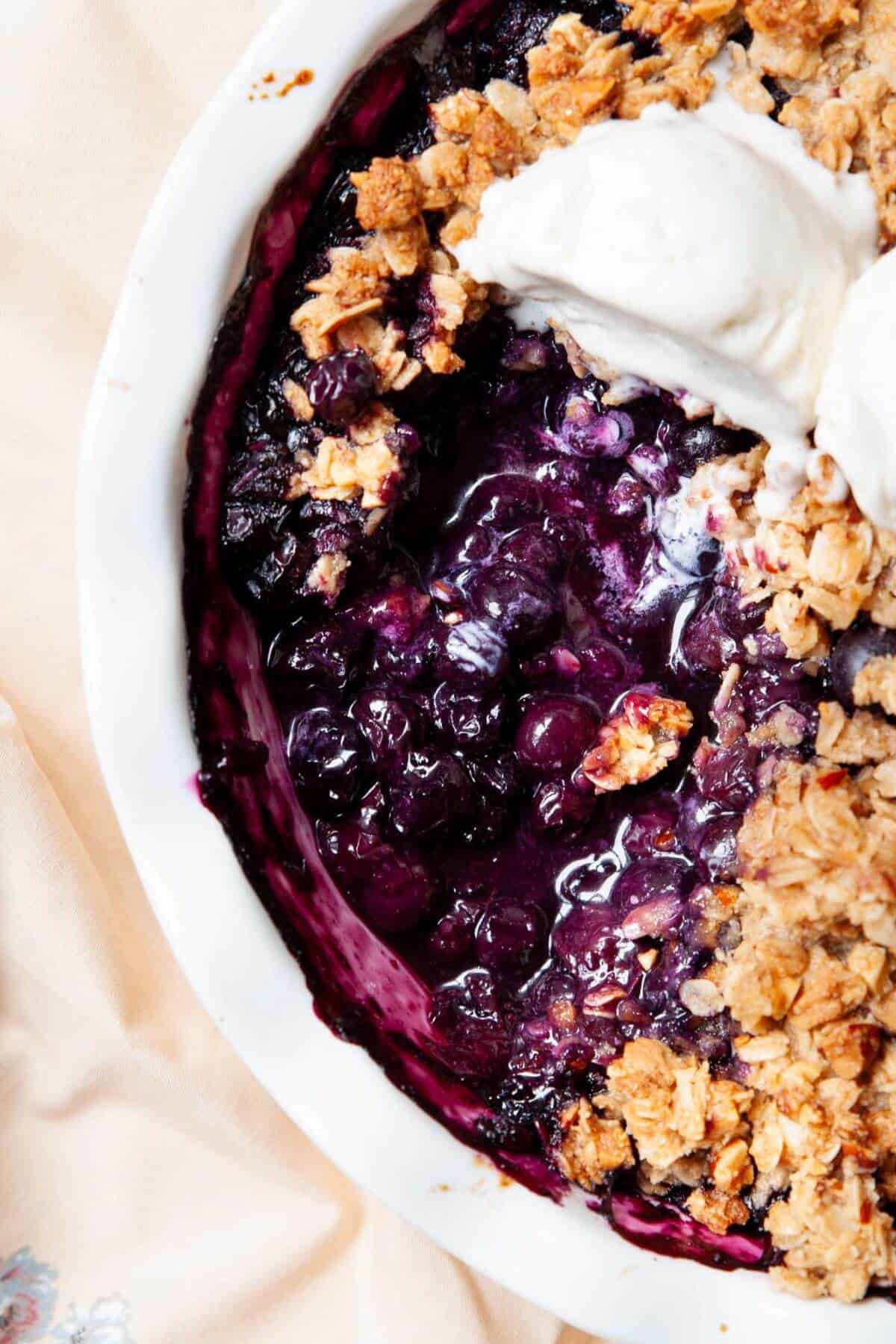 Spoon scooping blueberry crisp to show the jammy filling under the crumble topping.