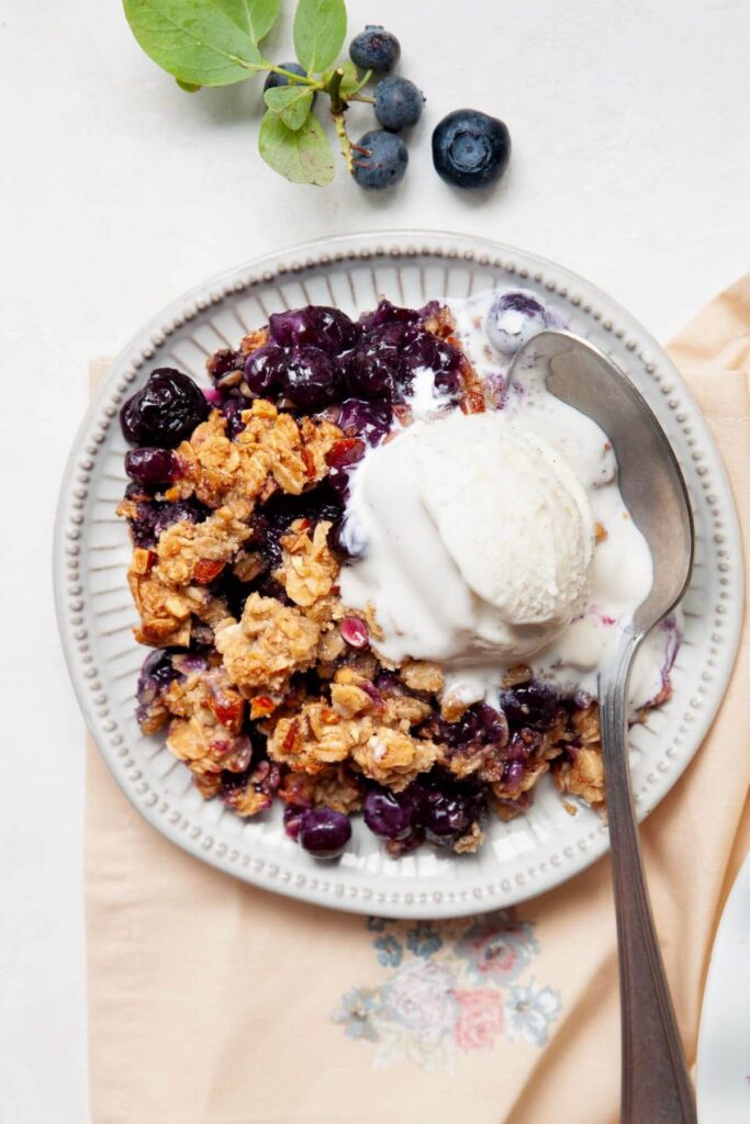 gluten-free blueberry crisp on a plate with vanilla ice cream