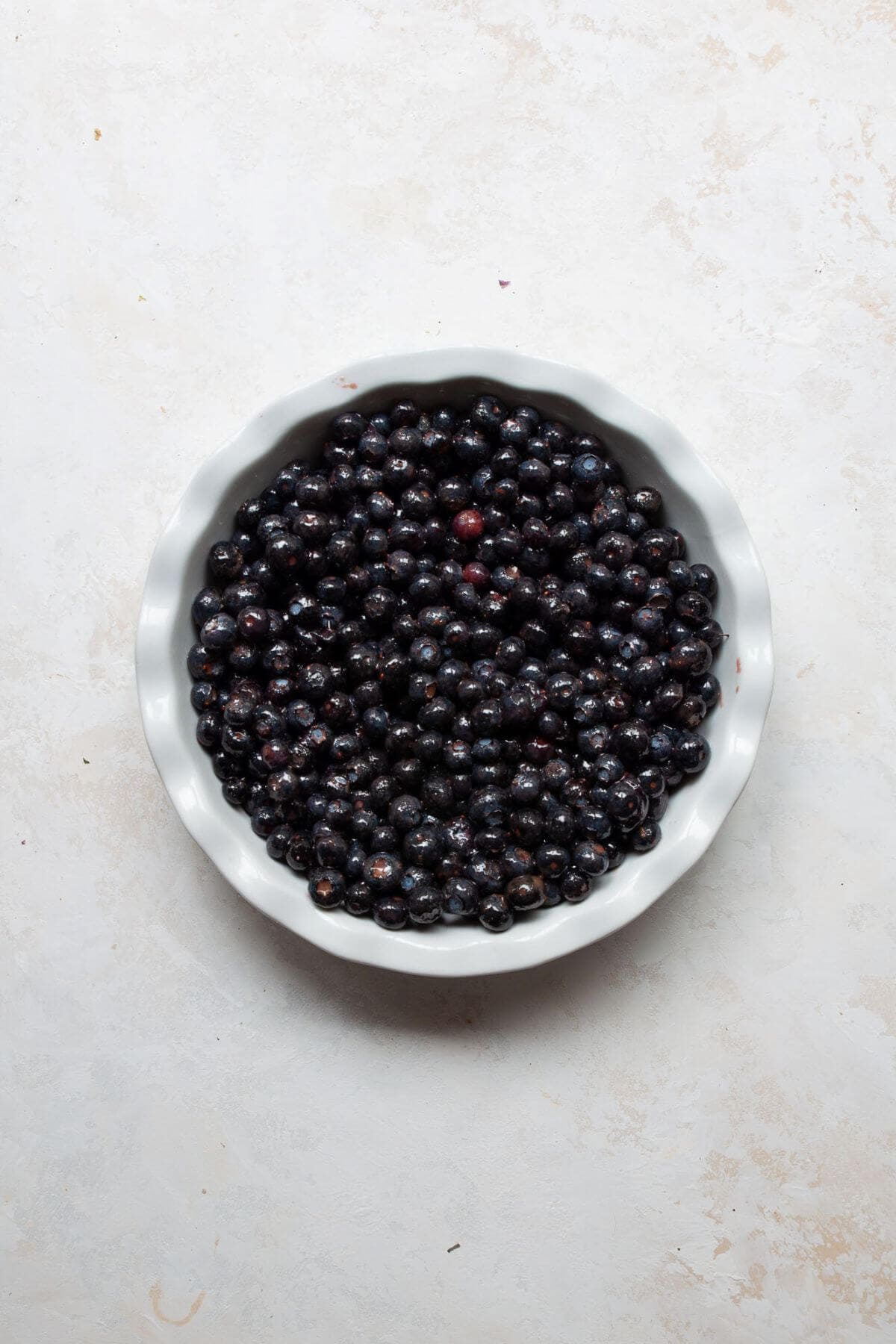 Blueberries spread evenly in a greased round baking dish before adding the crumble topping.