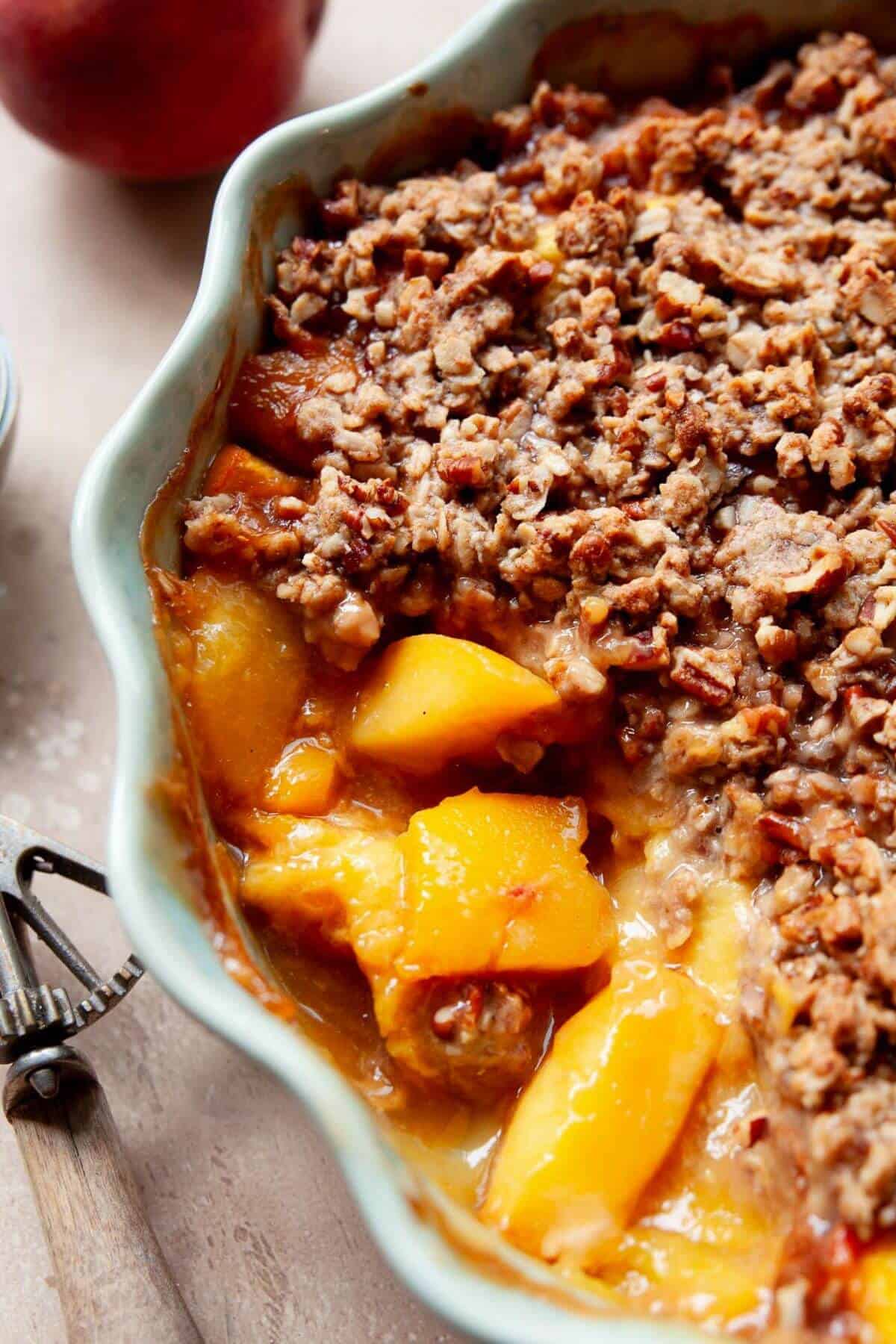 Close-up of healthy peach crisp with jammy peaches and crispy oat topping.