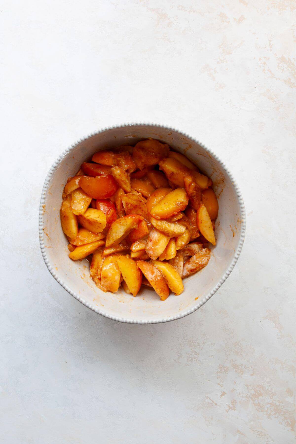Peach slices tossed with maple syrup, lemon juice, and cornstarch for peach crisp