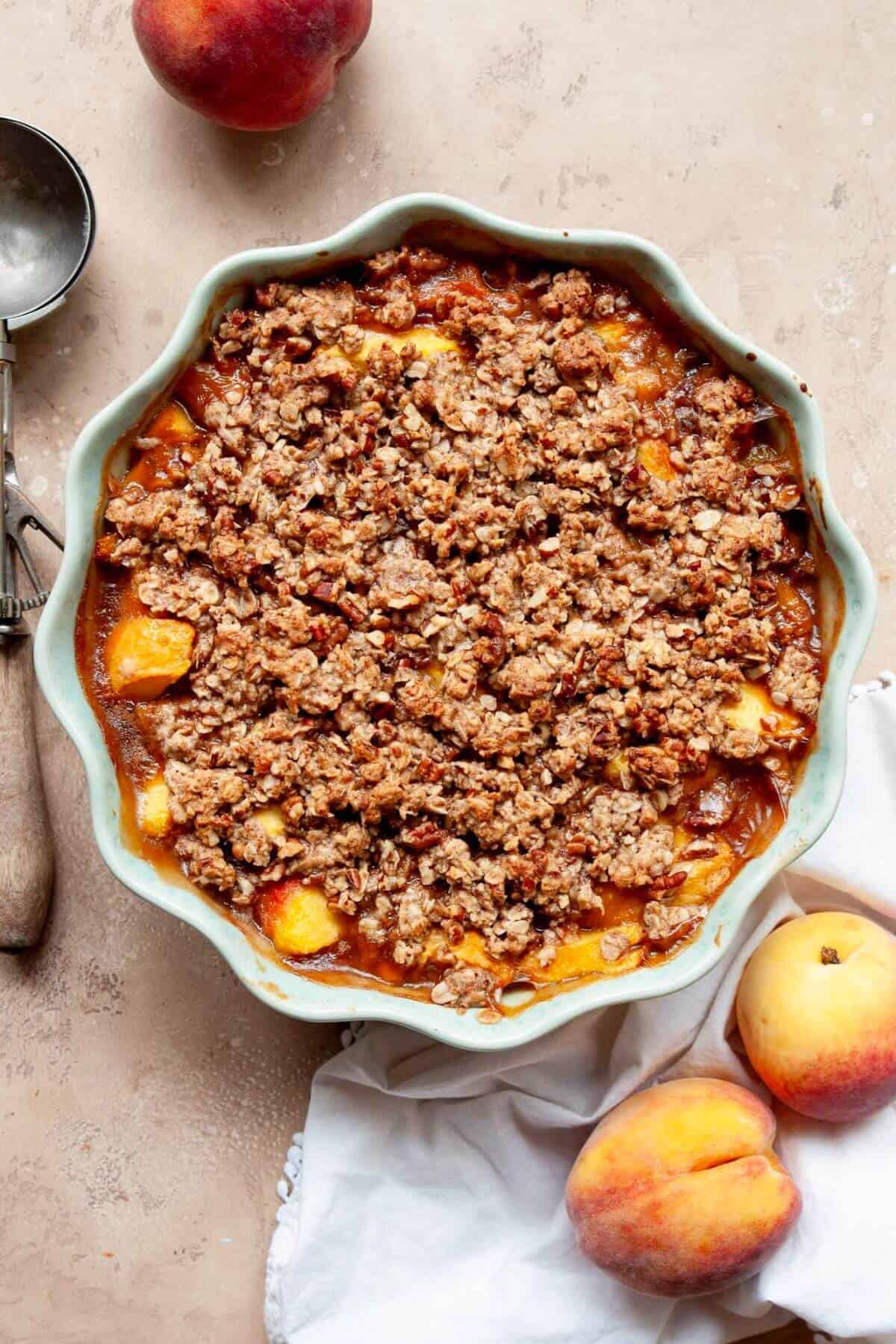 Baked healthy peach crisp with bubbling at the edges and a golden oatmeal crumble on top.