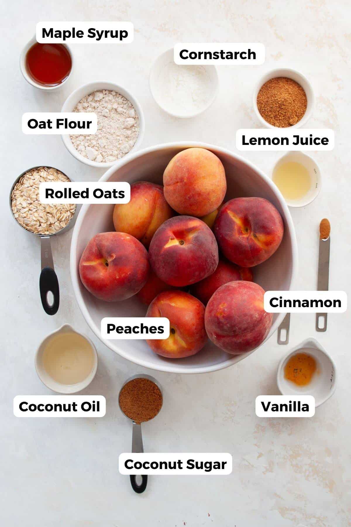 Ingredients for healthy peach crisp including fresh peaches, oats, maple syrup, coconut sugar, cornstarch, vanilla and coconut oil.