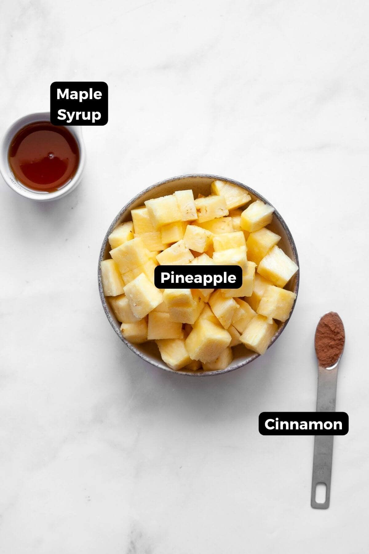 All ingredients in air fryer pineapple including: pineapple chunks, maple syrup, and cinnamon.