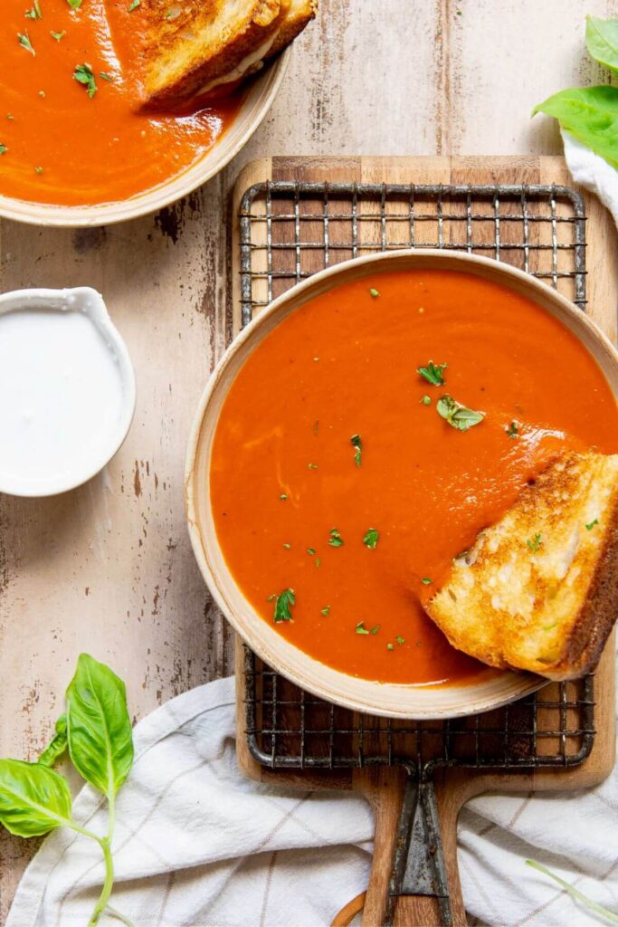 gluten-free tomato soup in a bowl with a grilled cheese