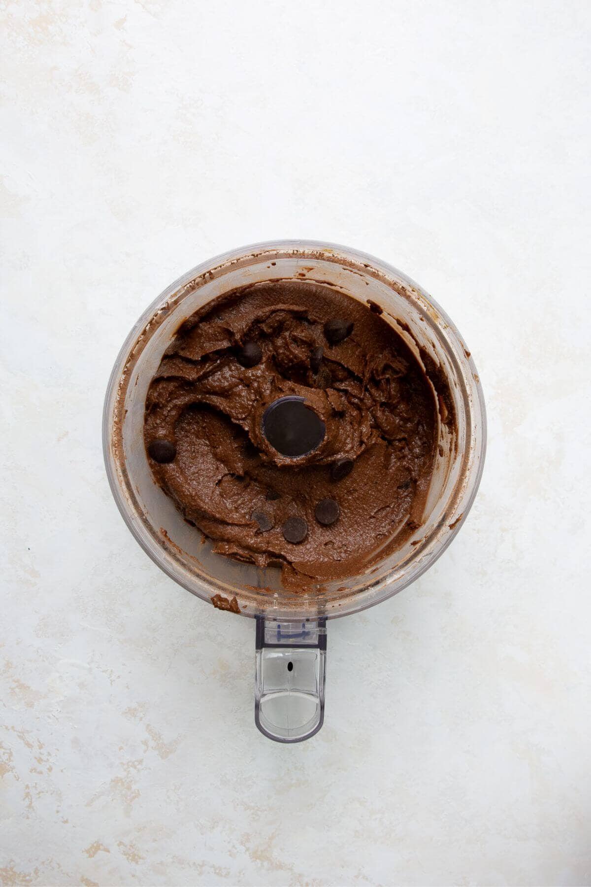 Chocolate chips folded into chickpea brownie batter in a food processor.