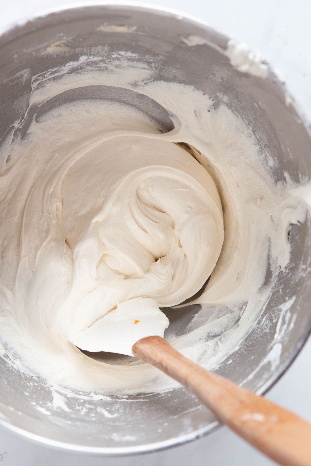 Healthy cream cheese yogurt frosting in a mixing bowl, whipped smooth and fluffy for topping gluten-free pumpkin cookies.