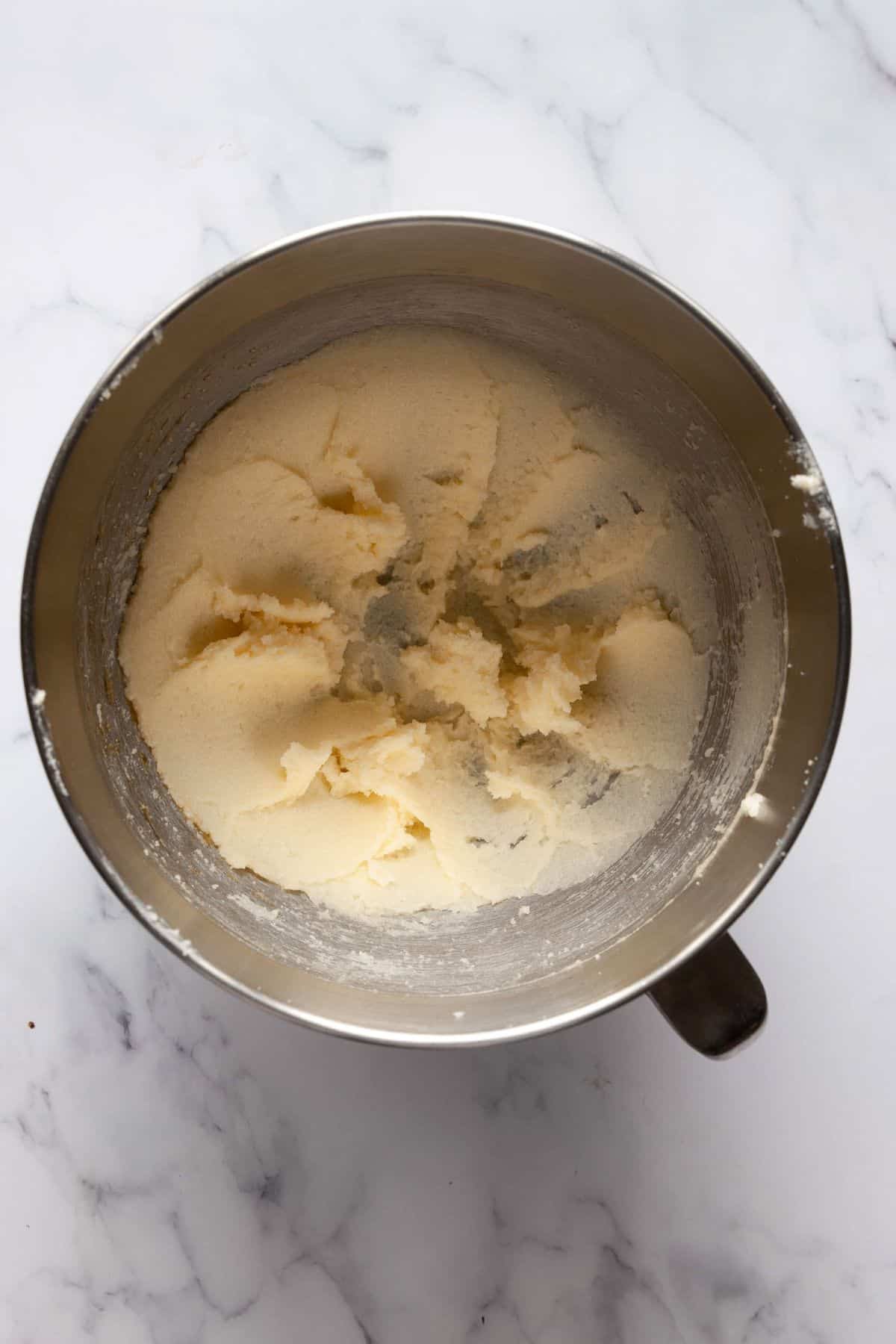 Creaming butter and sugar together in a mixing bowl until light and fluffy for gluten-free pumpkin cookie dough.