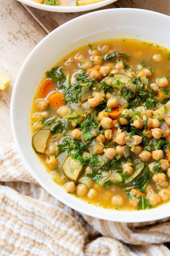 high protein lemony Greek chickpea soup in a bowl with zucchini and carrots