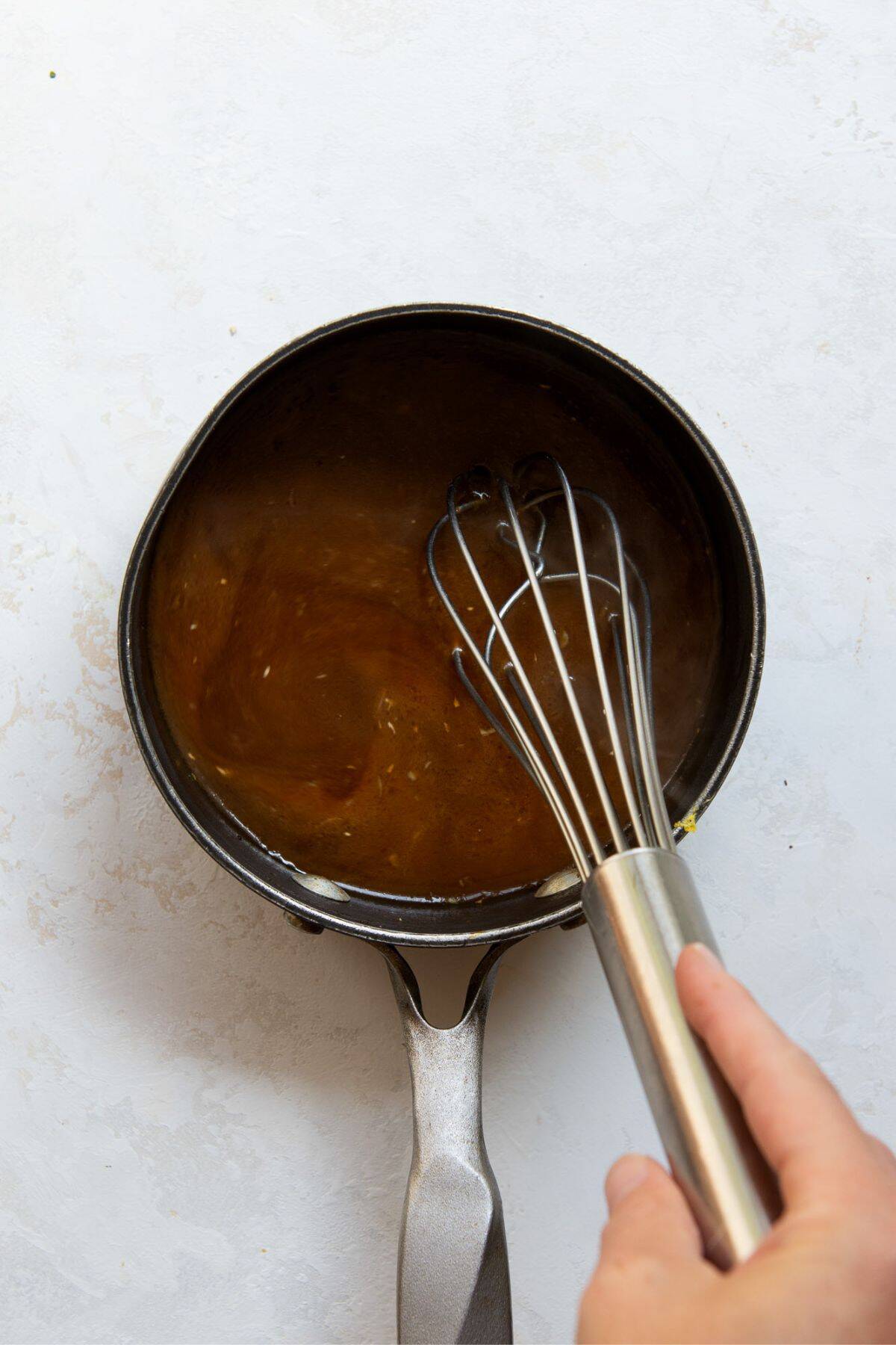 Whisking homemade healthy teriyaki sauce in a sauce pan.
