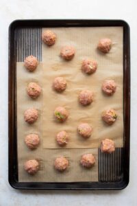 raw gluten-free Asian turkey meatballs in a baking sheet before baking