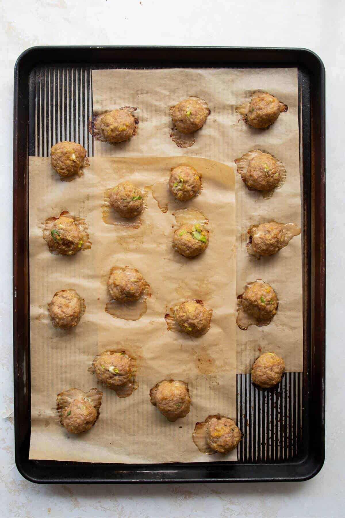 Cooked meatballs on a baking sheet.