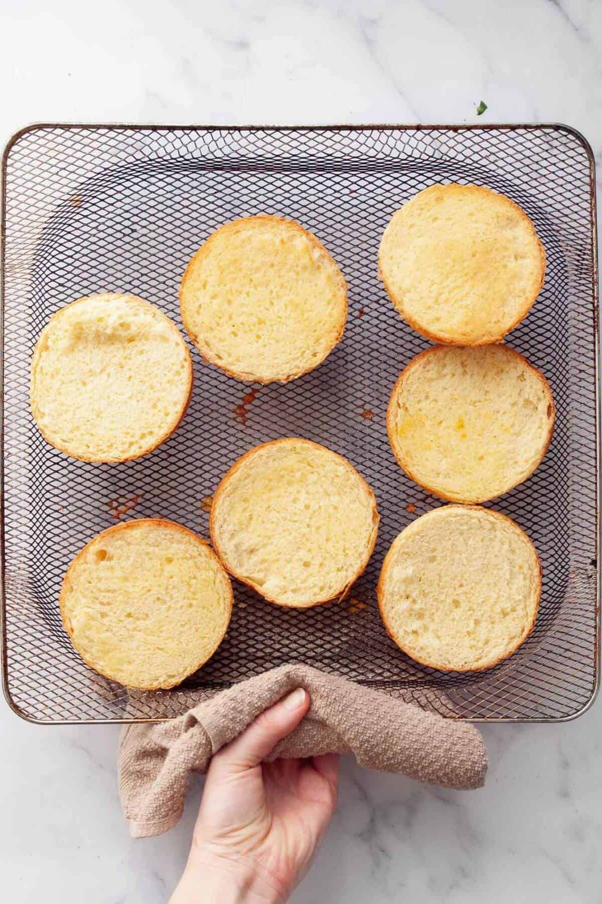 Toasted hamburger bun in an air fryer basket.